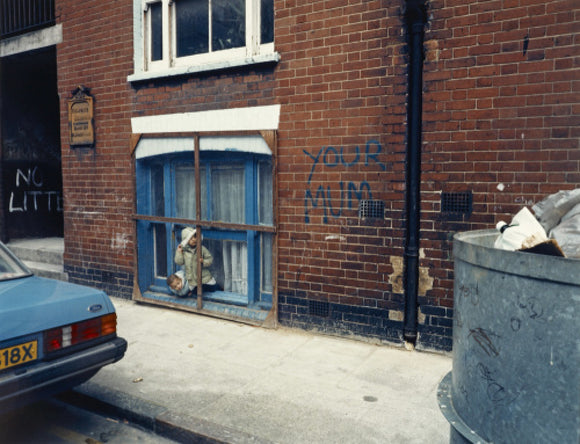 Two children looking out of a window; 1986
