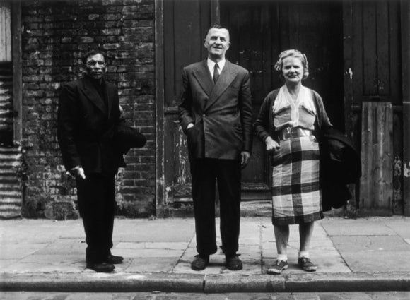Three people stand on street facing the camera: 1961