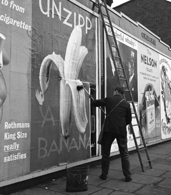 Man pastes up a billboard advertisement. c.1955